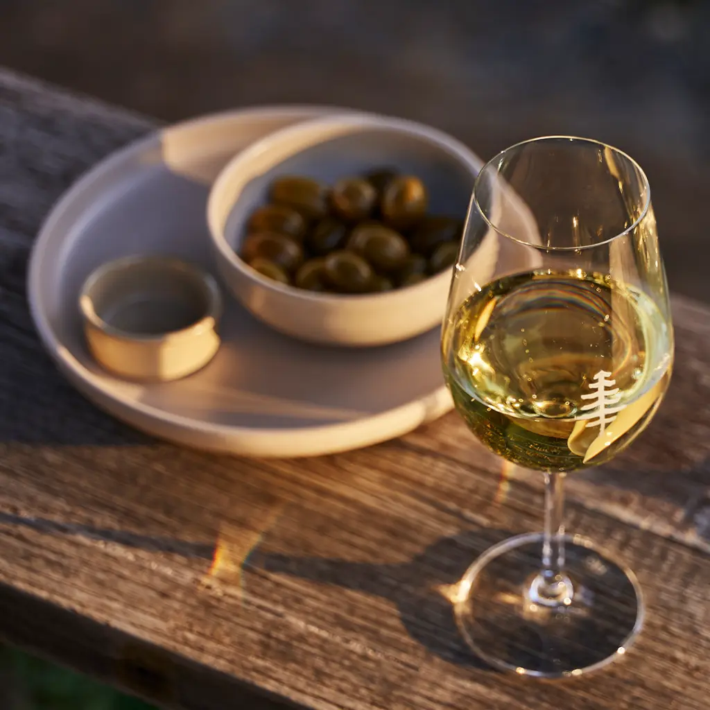 Wine glass next to a plate of olives